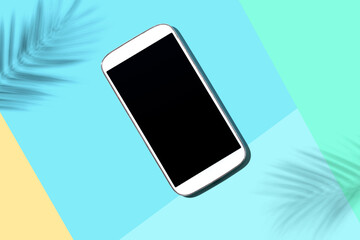 Smartphone with tropical palm leaves and shadow - flat lay