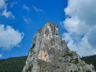 A sharp and steep cliff pointed towards the sky in Bicazului Gorges, Carpathia, Romania. An Christian-Orthodox Cross was built on top of the rocky crag.  © Alexandru V