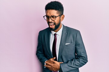 Handsome hispanic business man with beard wearing business suit and tie with hand on stomach because nausea, painful disease feeling unwell. ache concept.