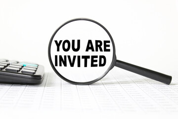 words YOU ARE INVITED in a magnifying glass on a white background. business concept