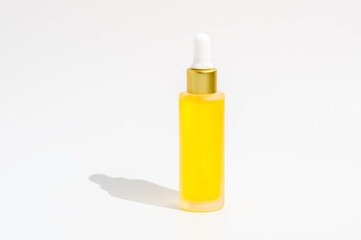 Dropper bottle of yellow serum or essential oil isolated on white background. Organic skin care cosmetics with Vitamin C. Wellness, spa and beauty treatment concept. Product mockup