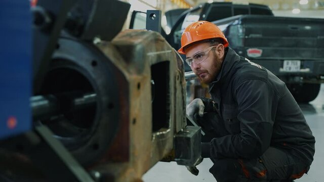 This video shows an industrial garage. A mechanic observing the undercarriage reboring procedure.