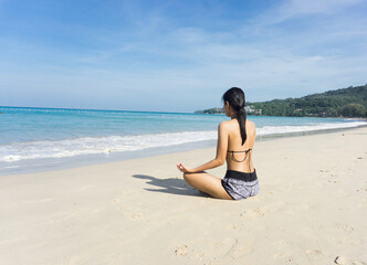 Fototapeta na wymiar Asian woman sitting yoga at the beach, white sand beach, health concept.