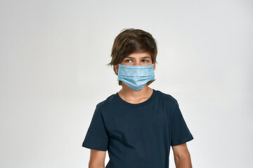 Little sportive boy child in sportswear wearing medical mask, looking aside, standing isolated over white background