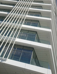 Close up of a modern office building with balconies and vertical sun shades.