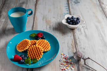 blueberries, raspberries and waffles on a rustic white wooden background