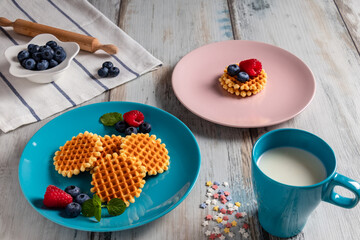 blueberries, raspberries and waffles on a rustic white wooden background