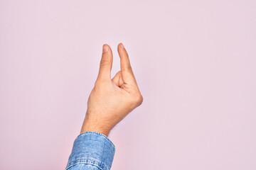 Hand of caucasian young man showing fingers over isolated pink background picking and taking invisible thing, holding object with fingers showing space