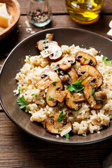 Risotto with brown champignon mushrooms on wooden background. 