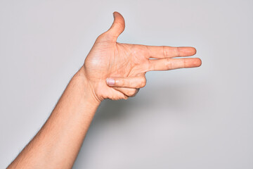 Hand of caucasian young man showing fingers over isolated white background gesturing fire gun weapon with fingers, aiming shoot symbol