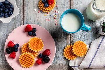 blueberries, raspberries and waffles on a rustic white wooden background