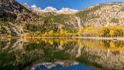 Water reflection of yellow autumn woods with Snow cap mountain peak of Ordesa National park