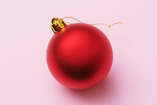 Red Christmas tree toy in the shape of a ball on a pink background, top view