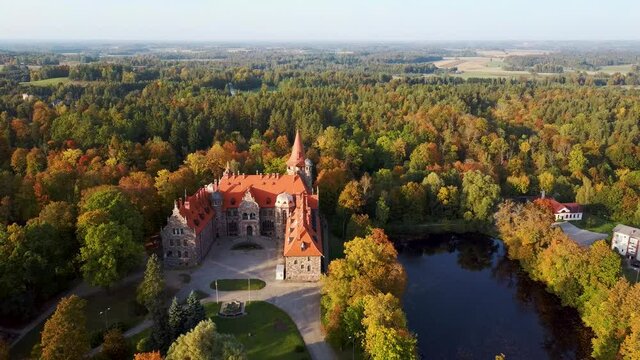 Cesvaine Medieval Castle in Latvia  From Above Top View. A Manor House of the Late 19th Century, a Building of Stones With a Brown Tiled Roof. Cesvaine Palace in Beautiful Autumn Day. Aerial Dron 4k S