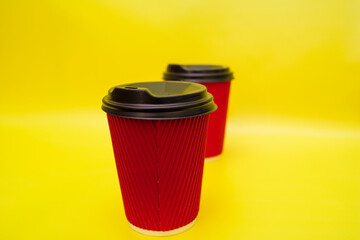 Red paper cups with takeaway coffee on yellow background