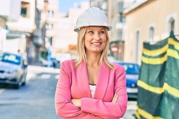Young caucasian architect with arms crossed smiling happy standing at the city.