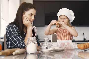 Family in a kitchen. Beautiful mother with little daughter. Woman in a black shirt.