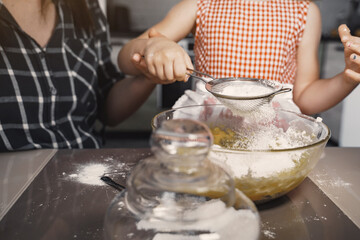 Family in a kitchen. Beautiful mother with little daughter. Woman in a black shirt.