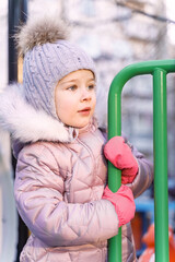portrait of a cute caucasian girl in winter clothes on a walk in the playground