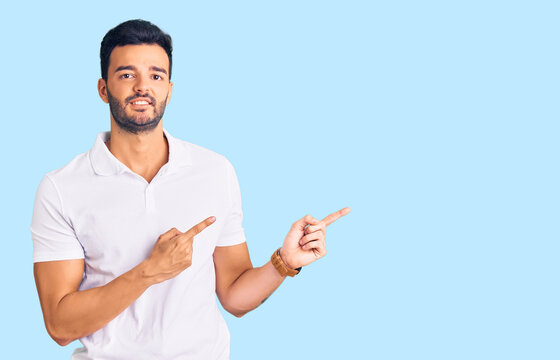 Young handsome hispanic man wearing casual clothes pointing aside worried and nervous with both hands, concerned and surprised expression