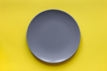 Ultimate gray plate on illuminating yellow background. Trend color of the year 2021. Minimal table...