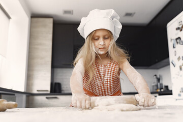 Little girl prepare the pie. Kid in the kitchen. Child with a flour.