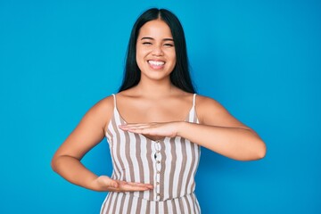 Fototapeta na wymiar Young beautiful asian girl wearing casual clothes gesturing with hands showing big and large size sign, measure symbol. smiling looking at the camera. measuring concept.