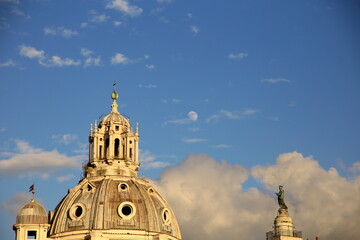Fototapeta na wymiar Domes of churches in Rome, on a day of blue sky with clouds and a full moon