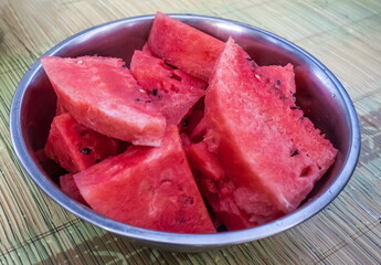 Watermelon slices without a crust in a metal dish close-up on the table background