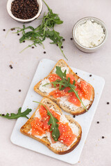 Salmon sandwich with cream cheese and arugula on marble table. top view
