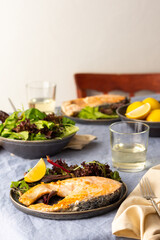 Fried salmon steak with salad in a plate , white wine in a glass, delicious hearty dinner or lunch