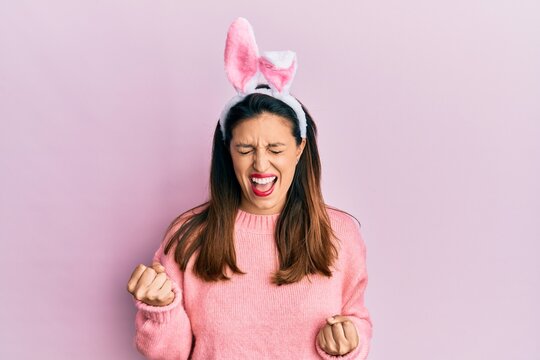 Beautiful hispanic woman wearing cute easter bunny ears celebrating surprised and amazed for success with arms raised and eyes closed