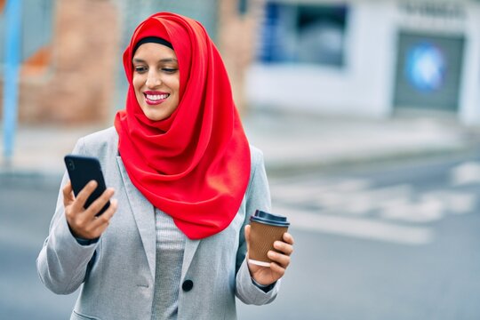 Young arab businesswoman using smartphone and drinking coffee at the city.