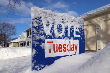 Vote sign "Vote Tuesday" covered in snow in a front yard
