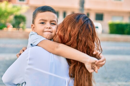 Adorable latin mother and son smiling happy hugging at the city.
