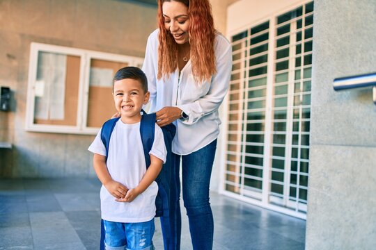 Adorable latin student boy and mom at school. Mother preparing kid putting up backpack.
