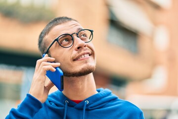 Young hispanic man smiling happy talking on the smartphone at the city.