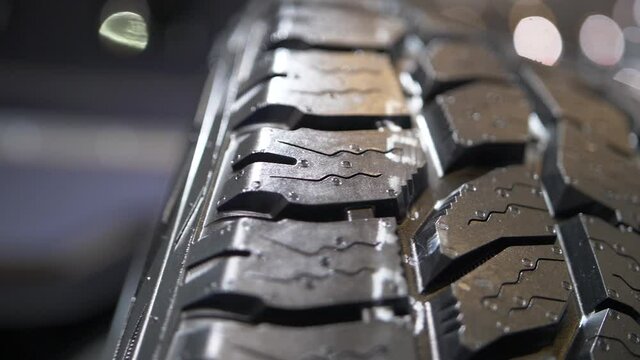 Smooth slowmotion close-up shot of a brand new car tyre, focus pulled.
