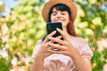 Young hispanic tourist girl wearing summer style using smartphone at the park.