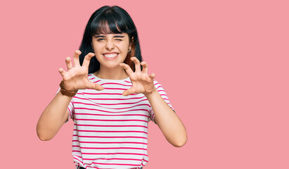 Young hispanic girl wearing casual clothes smiling funny doing claw gesture as cat, aggressive and...