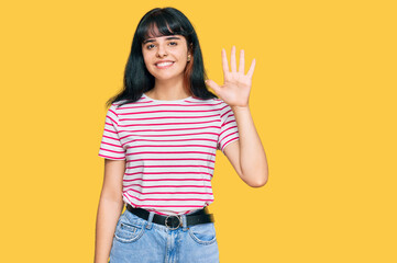 Young hispanic girl wearing casual clothes showing and pointing up with fingers number five while smiling confident and happy.