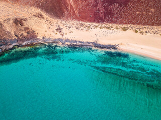 Aerial view of the jagged shores and beaches of La Graciosa island. Bathers on the beach of las...