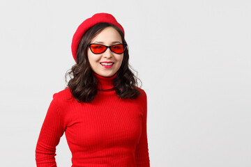 portrait of a young woman in a red beret, sweater and glasses on a white.