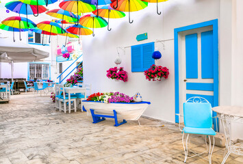 Beautiful street bar (restaurant) decoration with colorful umbrellas, old wooden boat and flowers....