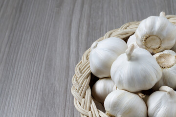 Garlic Cloves and Bulb in vintage organic woven basket on wooden background. spice is an herb that is grown around the world.