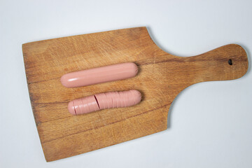 Sausages on a wooden board. A chopped sausage next to a whole sausage. meat product on a white background.