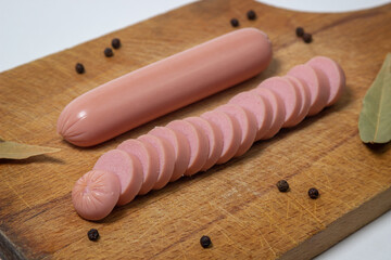 Sausages on a wooden board. A chopped sausage next to a whole sausage. meat product on a white...