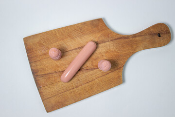 Sausages on a wooden board. A chopped sausage next to a whole sausage. meat product on a white background.