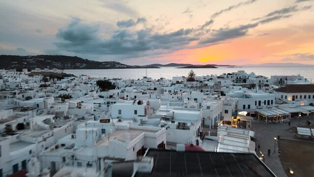 Aerial view flying over Mykonos town and a beautiful sunset on background