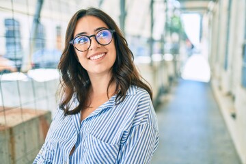 Young hispanic businesswoman smiling happy walking at the city